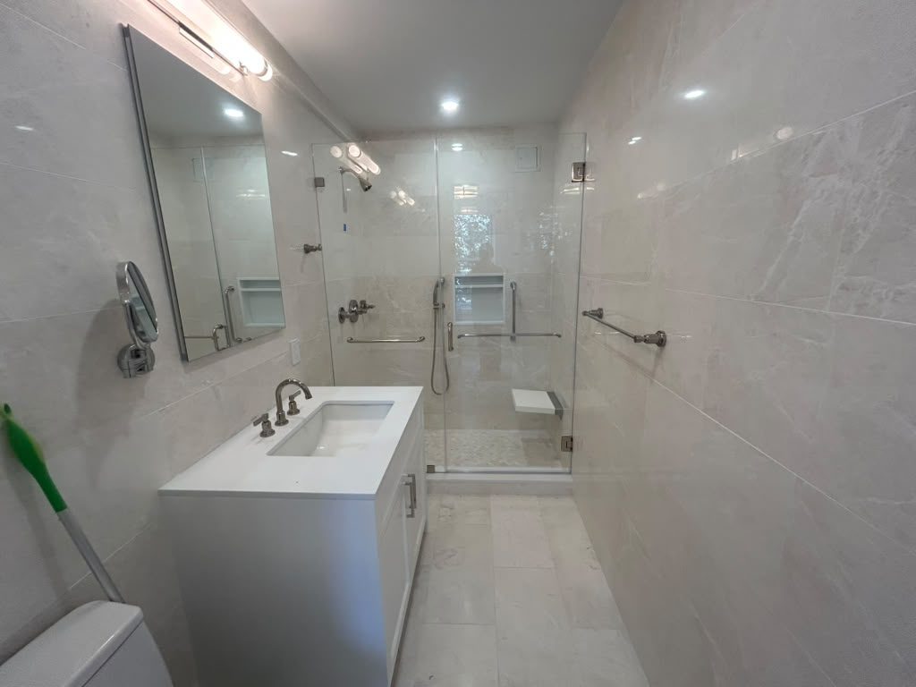 Spa-style bathroom with marble tile and a glass enclosure