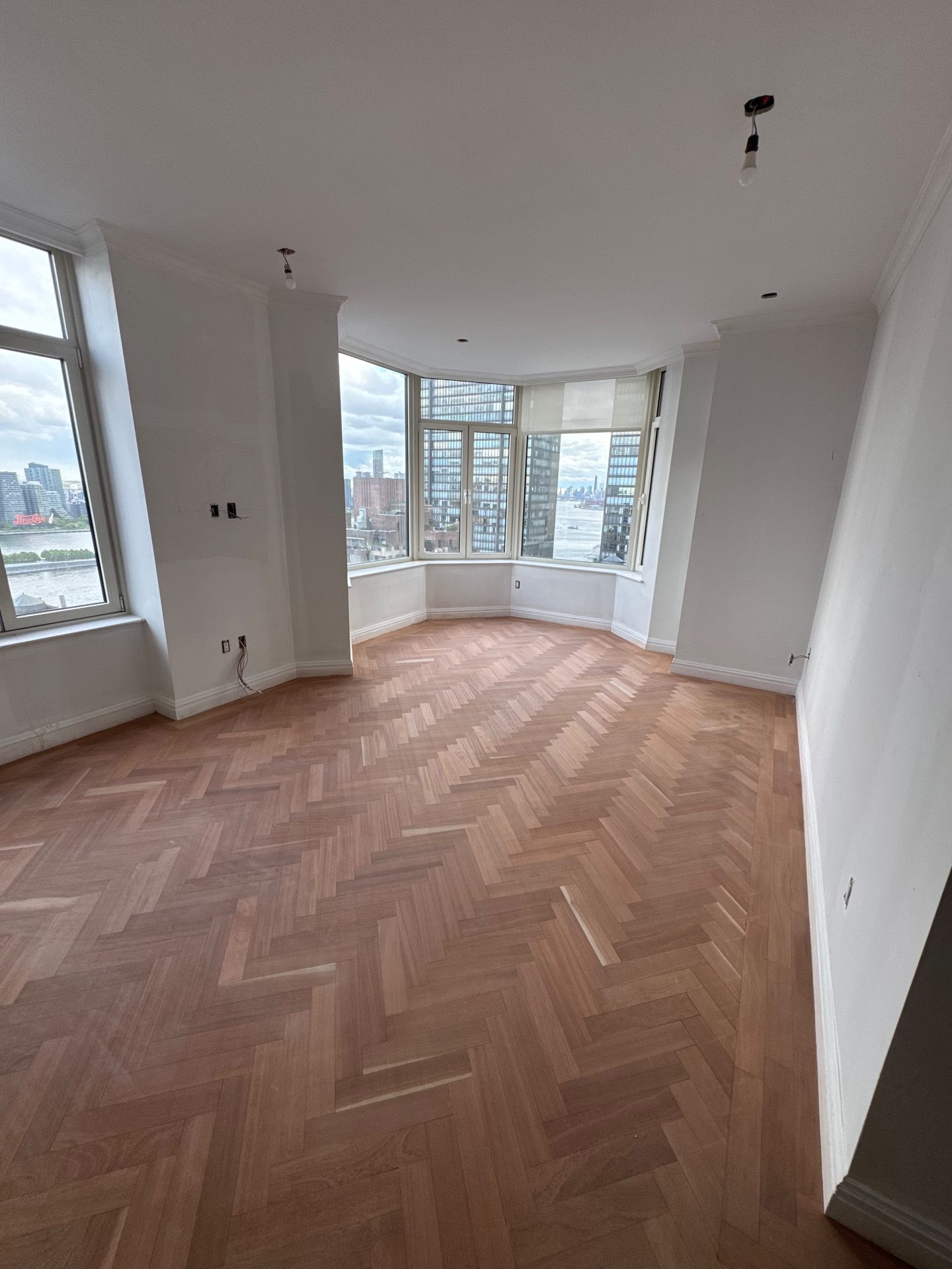 Herringbone floor beneath a bay window with a city view