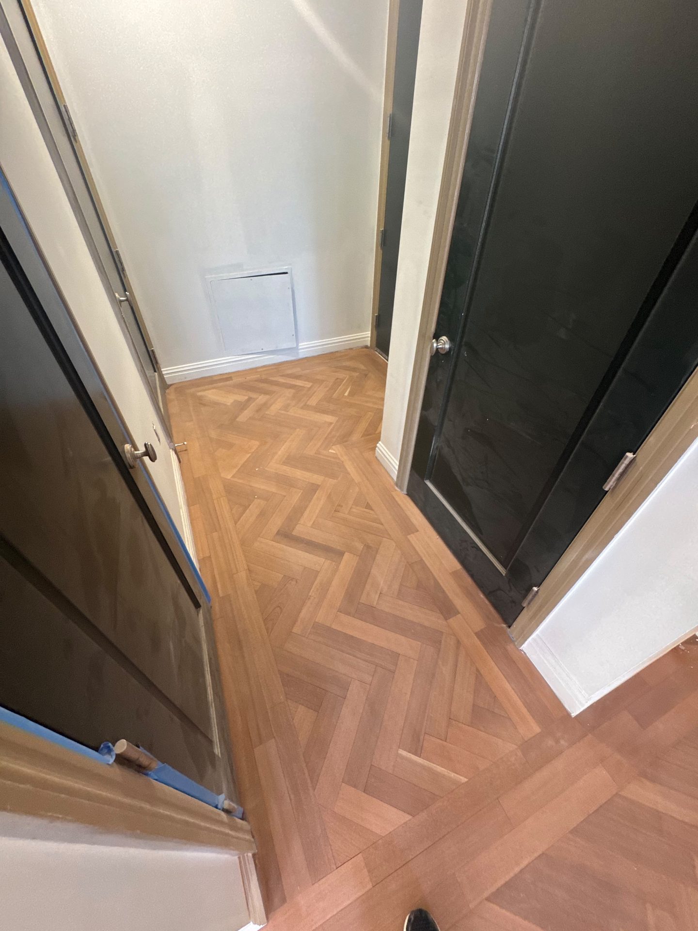 Herringbone flooring meeting a dark lacquered door