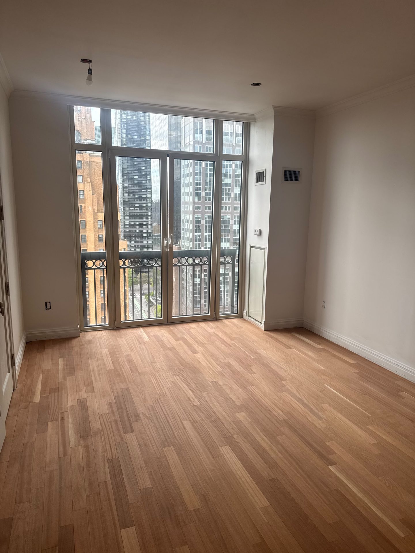 Freshly finished hardwood flooring in a room opening to a balcony and city view